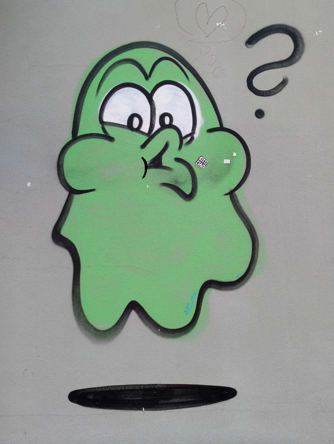 Sprayed green ghost making suprised face with a question mark next to its face, has a shadow under it to indicate that its floating. On a dark grey wall
