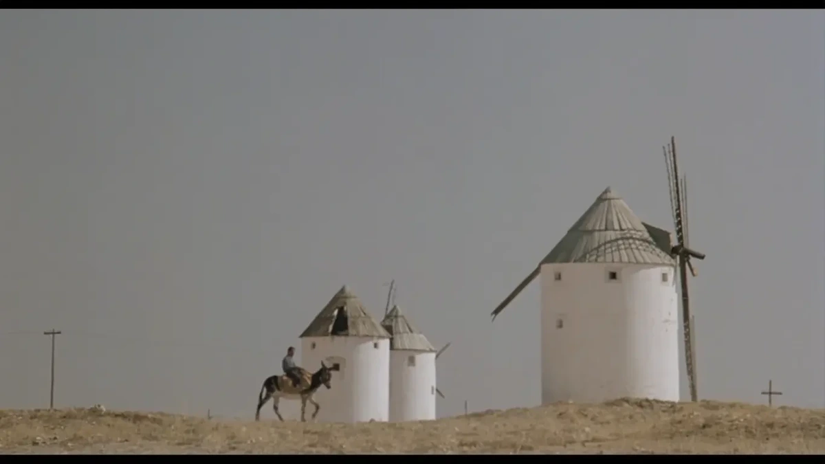 Screenshot from the film 'The Hit' - windmills, man on donkey