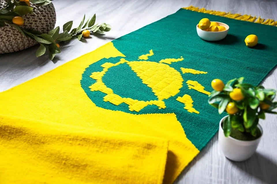A rug with the solarpunk symbol (Half of a Sun and Gear cog combined into one. half of the flag and the sun/cog is bright yellow, and the other half is green.