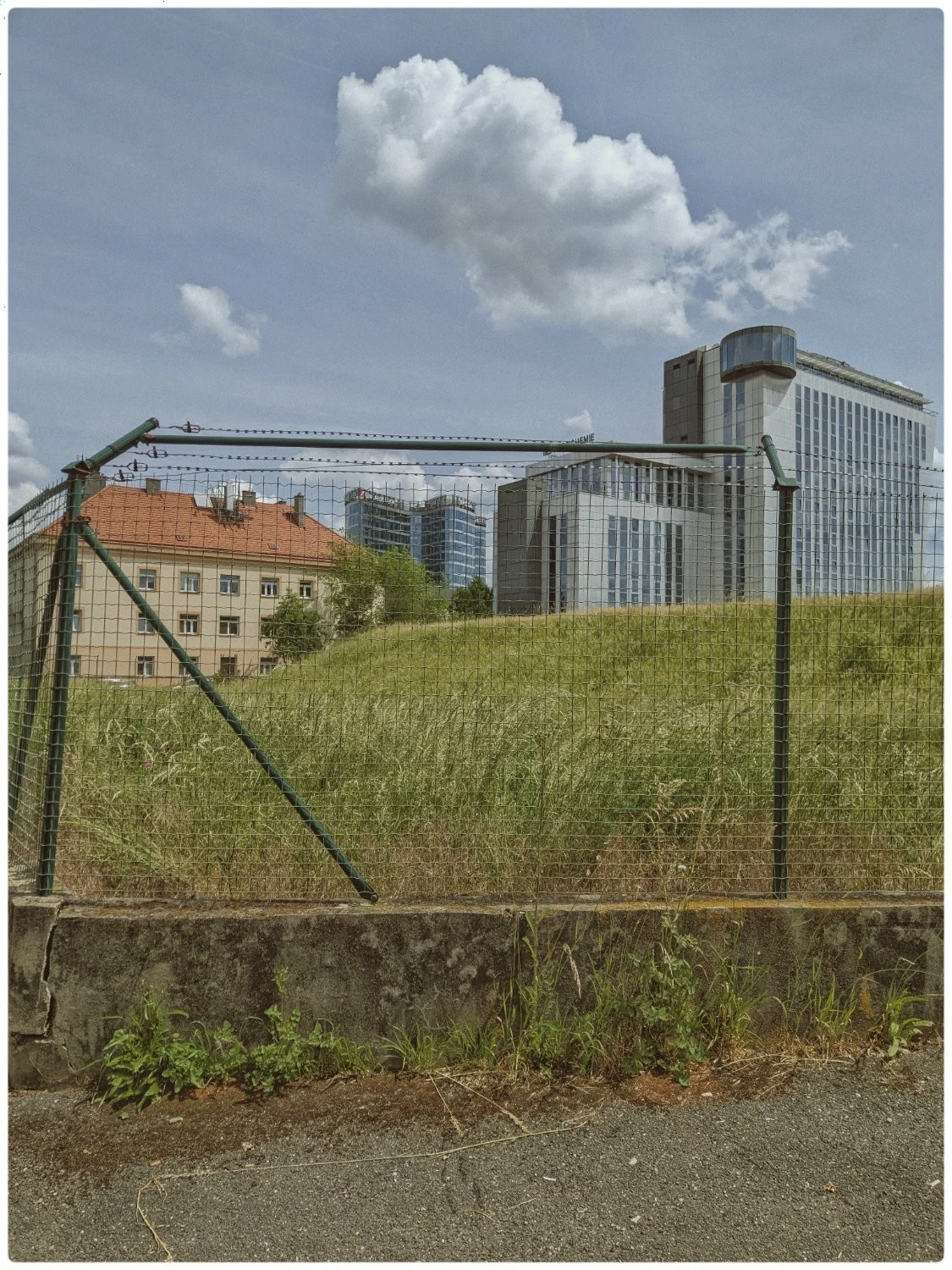 A cityscape trapped inside a barbed wire fence. 