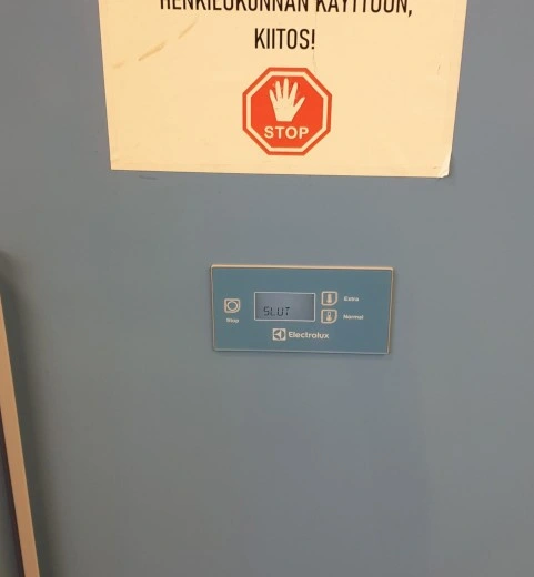 A clothes drying closet such as often used in children's daycare centre, saying "SLUT" on its electronic screen.