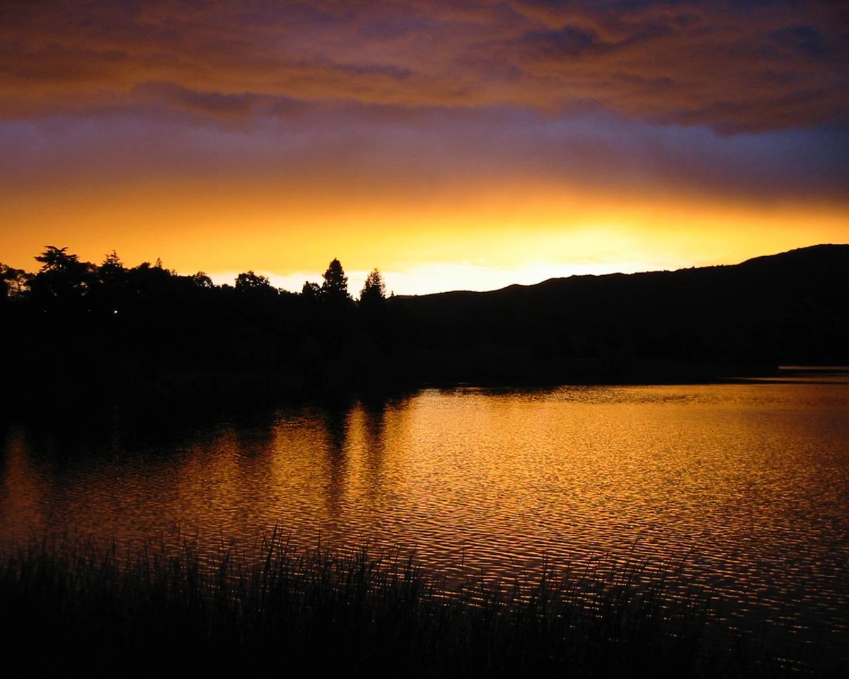 Sunset in the clouds, illuminating lake waters.