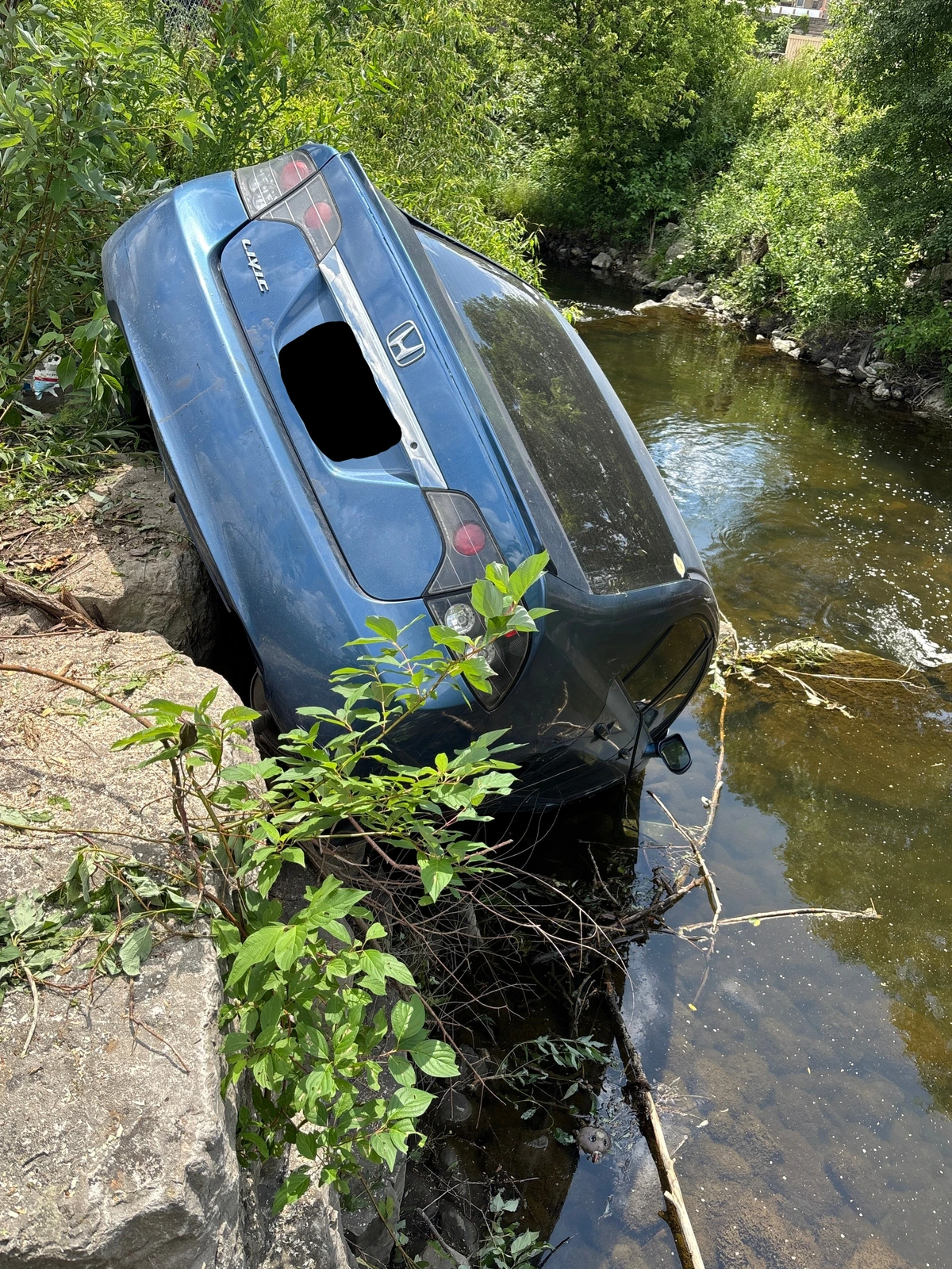 A blue car on its side in a creek