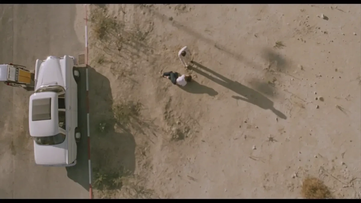 Screenshot from the film 'The Hit' - overhead view of hitman standing over hostage
