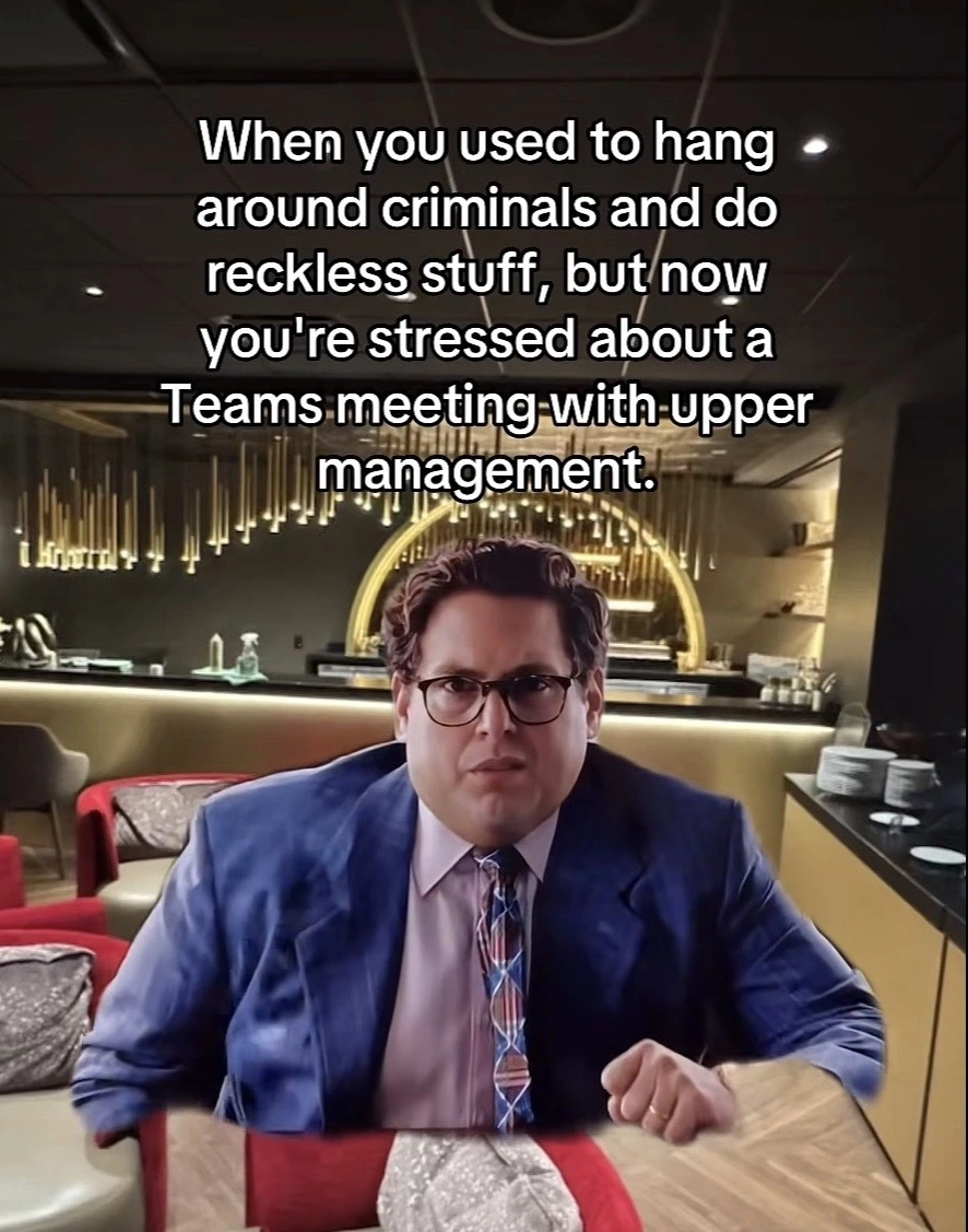 Man in a suit (a scene from a Jonah Hill movie) superimposed over a posh bar scene with the caption “When you used to hang around criminals and do reckless stuff, but now you're stressed about a Teams meeting-with-upper management.”