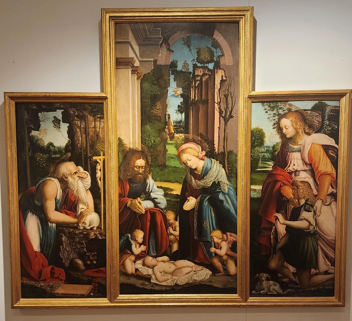 Simple triptych with three rectangular panels, the center one being taller and wider than the others. On the left panel is an old man kneeling against a rock and resting his hand on a skull while gazing at a crucifix. The center panel shows Joseph, Mary and three cherubs holding their palms together in a prayer posture while gazing down at the baby Jesus. On the right is an angel directing a kneeling boy, who is holding a fish on a line, to adore the child. A small dog is just below the boy's knee.